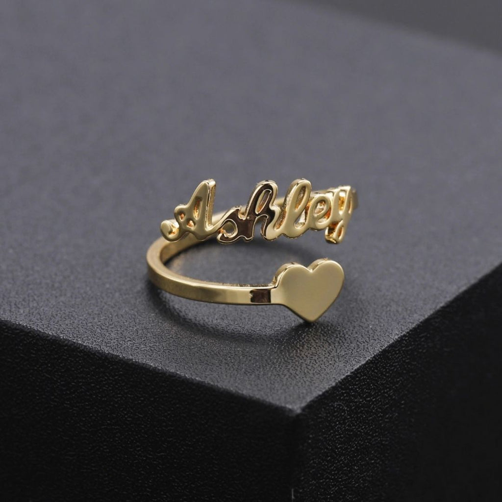 A personalized Heart Name Ring made of gold with engraved names and heart-shaped design